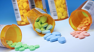 Image of prescription drug bottles with pills lying on a table.